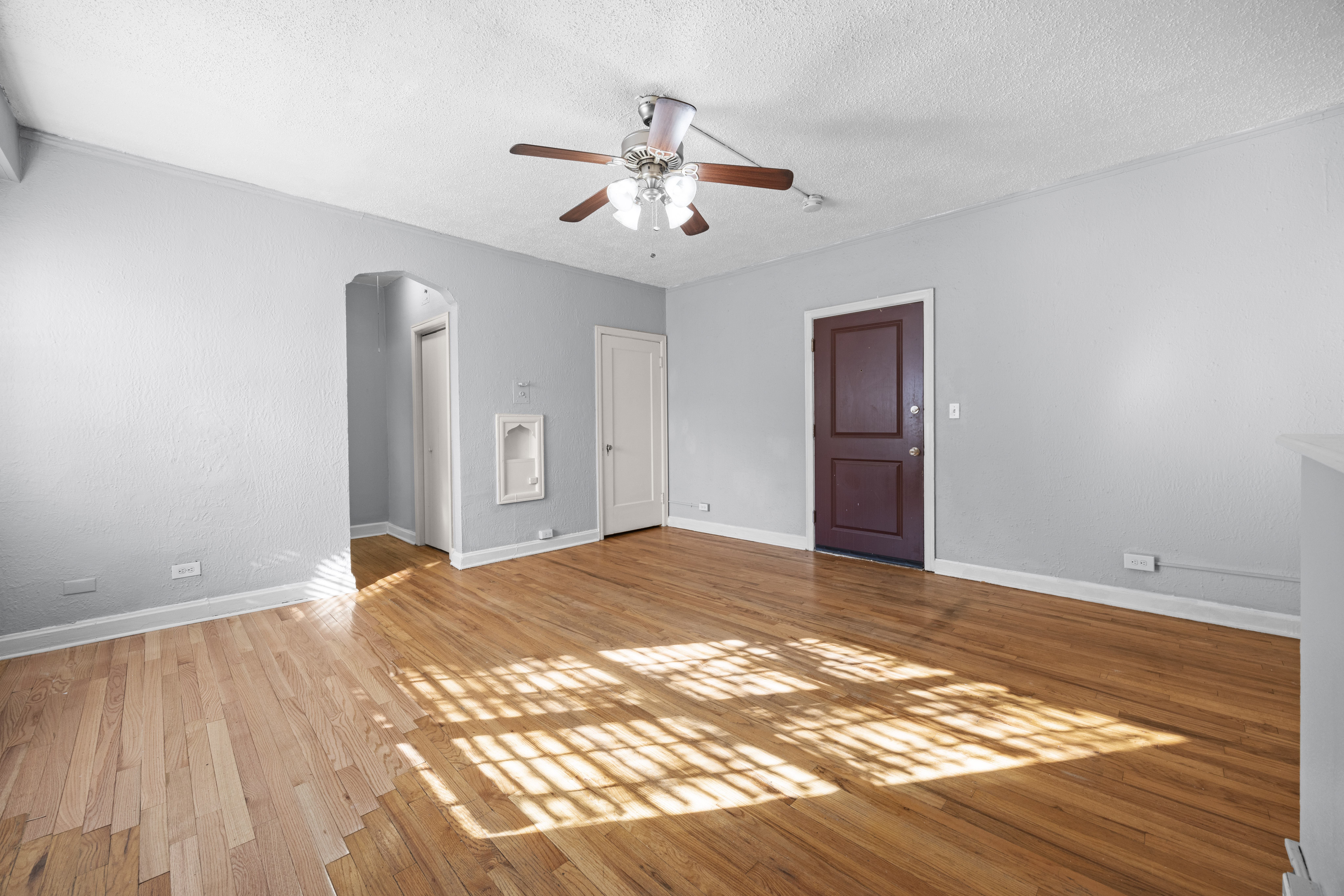 A room with a ceiling fan and wooden floors.